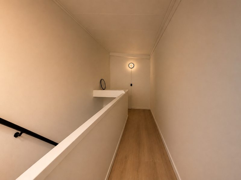 Spiegelglad afgewerkte wanden op een overloop met houten vloer